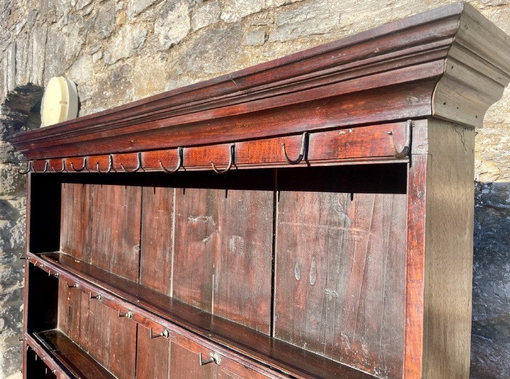 An antique dark oak Georgian dog kennel dresser featuring an open shelf rack above three drawers and two cupboard doors. View XI