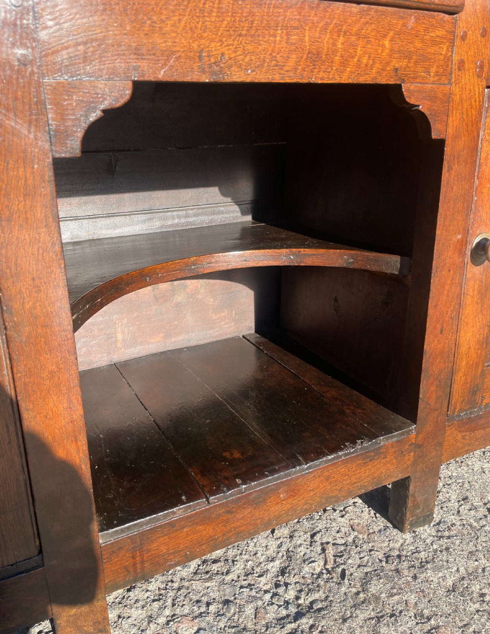 An antique dark oak Georgian dog kennel dresser featuring an open shelf rack above three drawers and two cupboard doors. View XII