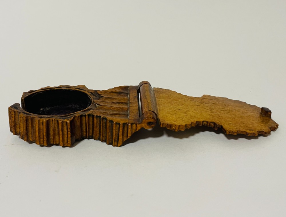 An antique carved wooden Black Forest pocket watch holder with leaf detailing on the base and a dark velvet-lined aperture for displaying a timepiece. View VIII