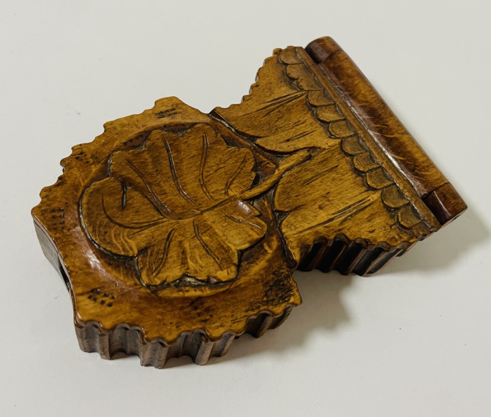 An antique carved wooden Black Forest pocket watch holder with leaf detailing on the base and a dark velvet-lined aperture for displaying a timepiece. View XI