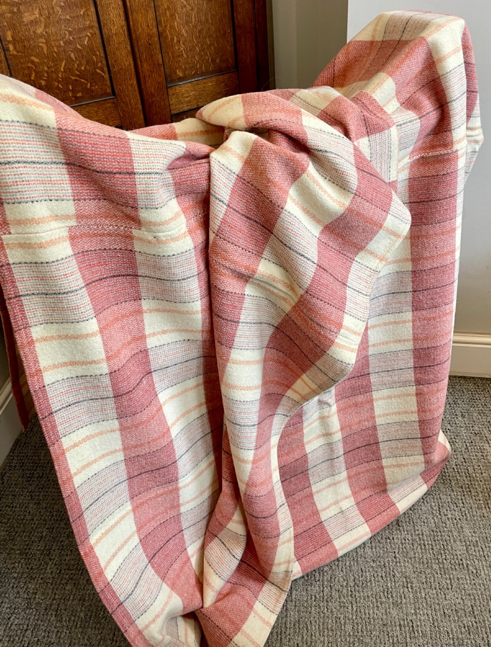 A large woven Welsh wool blanket featuring a pink, cream, and subtle yellow plaid grid design. View III