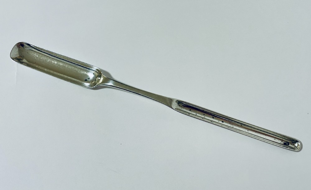A Georgian Irish sterling silver double-ended marrow scoop resting horizontally against a plain white background.