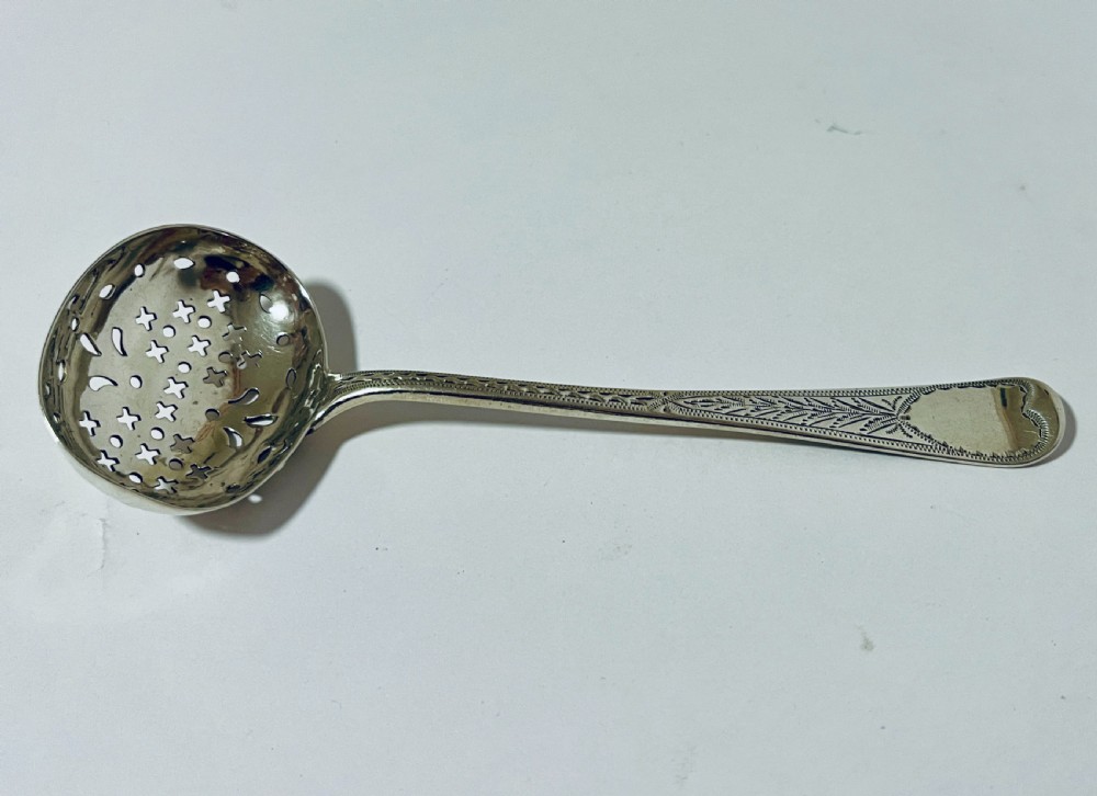 An antique Georgian silver sugar sifter spoon featuring a pierced bowl and an engraved handle. View II