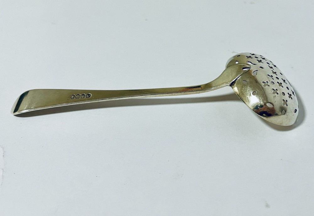 An antique Georgian silver sugar sifter spoon featuring a pierced bowl and an engraved handle. View VI
