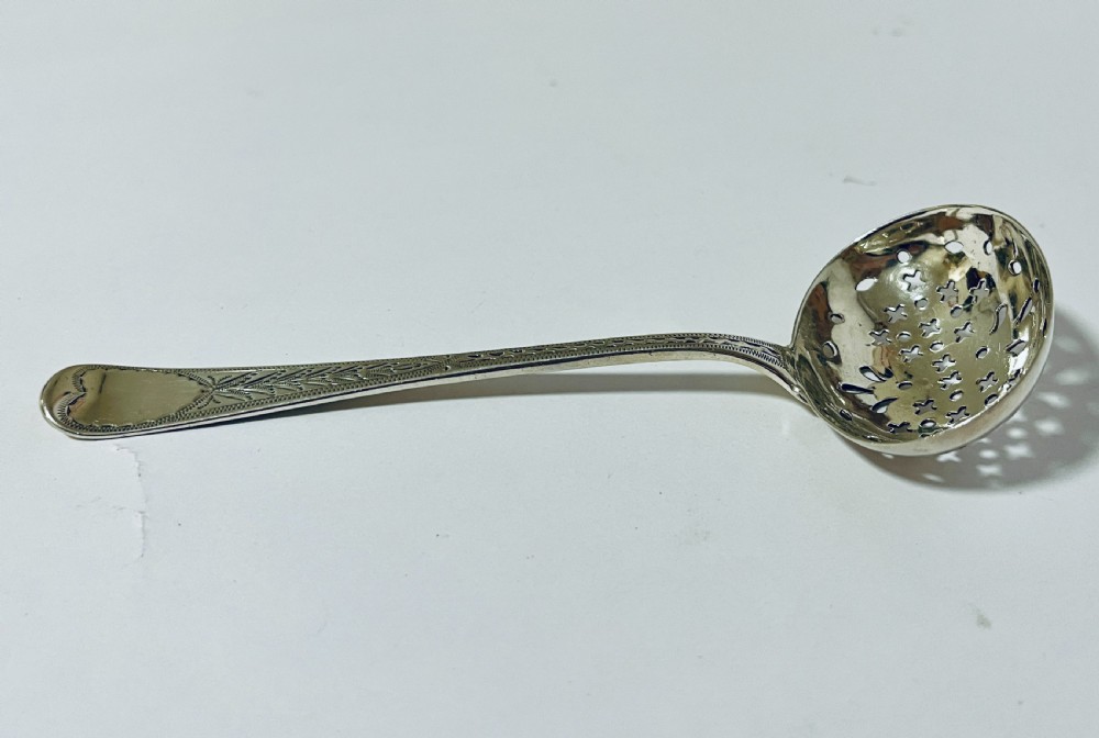 An antique Georgian silver sugar sifter spoon featuring a pierced bowl and an engraved handle. View IX