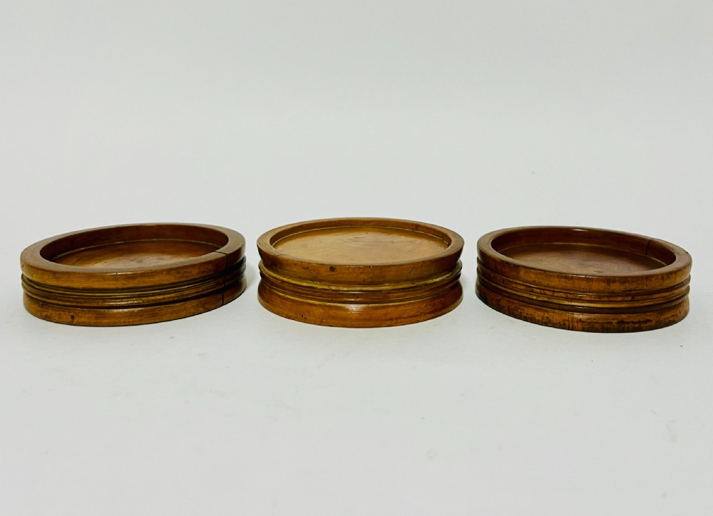 A set of three circular turned boxwood apothecary pill rounders with shallow central recesses and concentric moulded edges. View III
