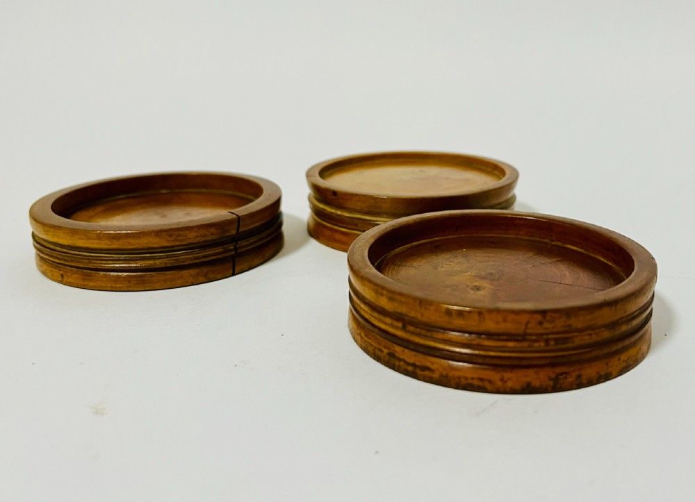 A set of three circular turned boxwood apothecary pill rounders with shallow central recesses and concentric moulded edges. View V