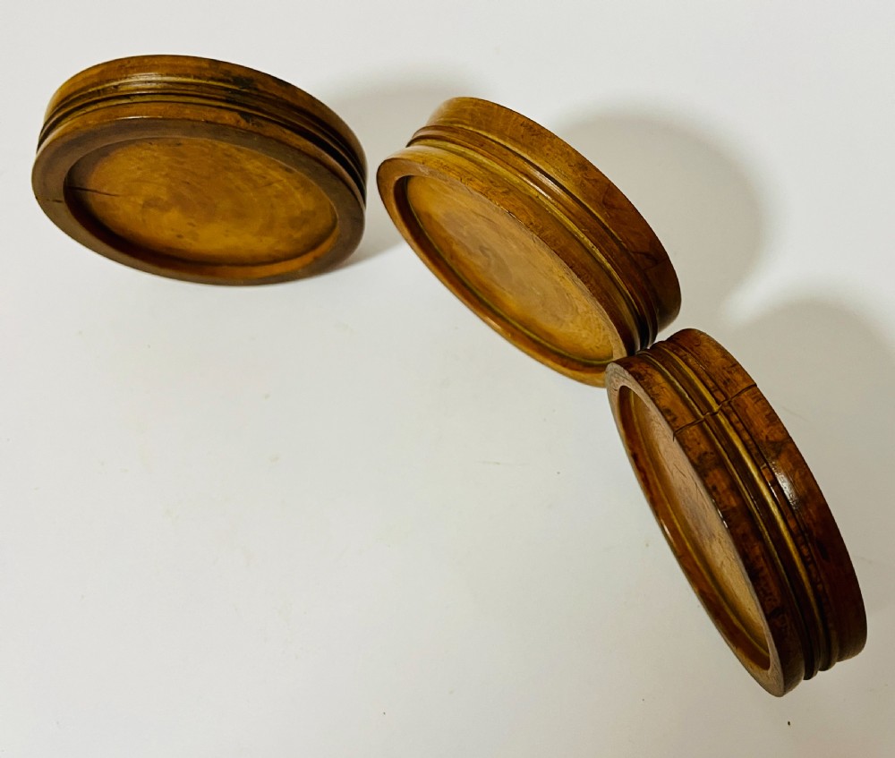 A set of three circular turned boxwood apothecary pill rounders with shallow central recesses and concentric moulded edges. View X