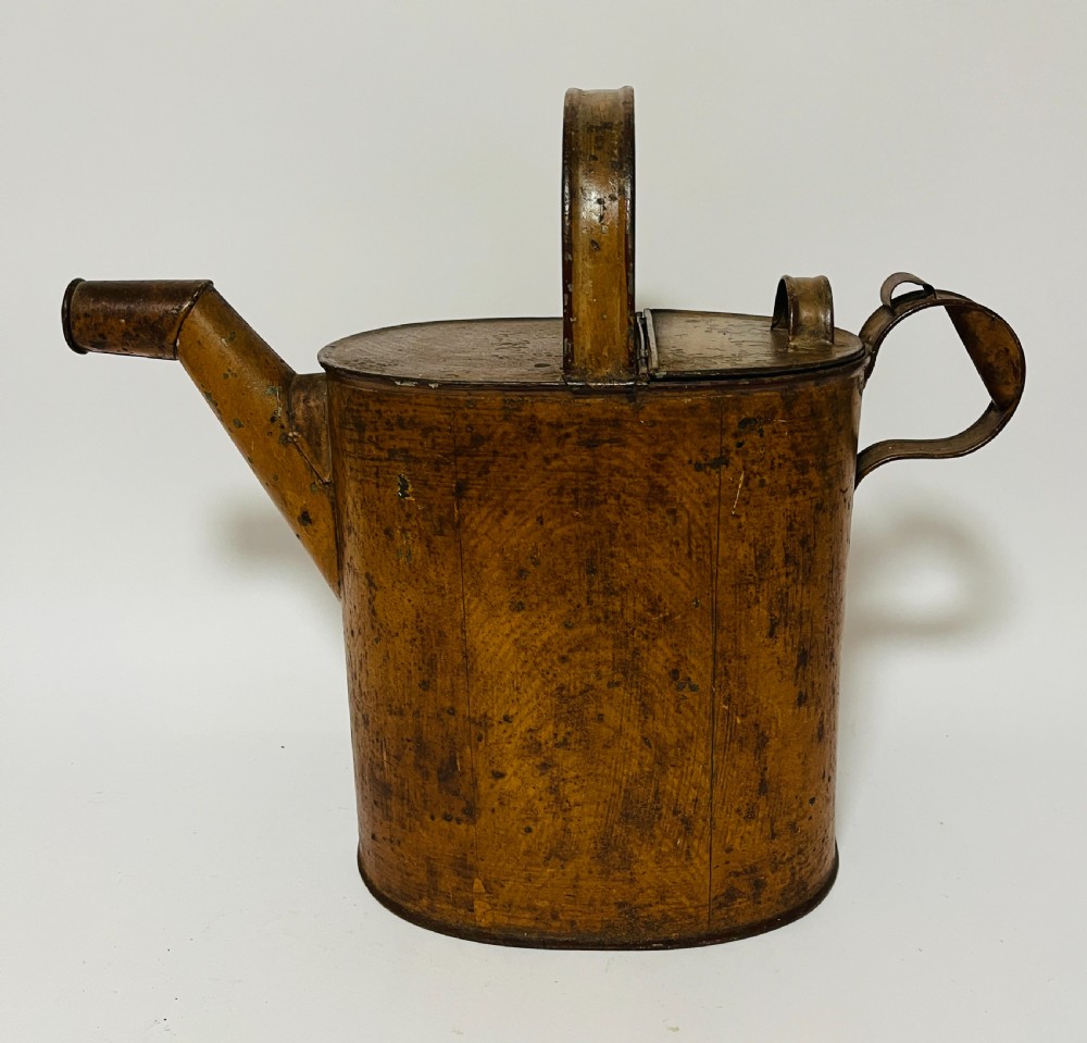 A Victorian painted tinplate hot water can featuring an overhead carrying handle, side loop handle, hinged lid, and angled spout.