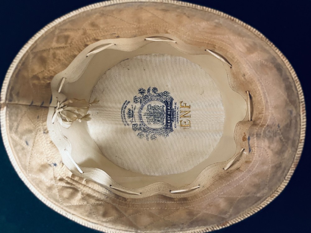 A black silk plush top hat resting on top of a bucket-shaped tan leather carrying case with a metal lock. View VIII