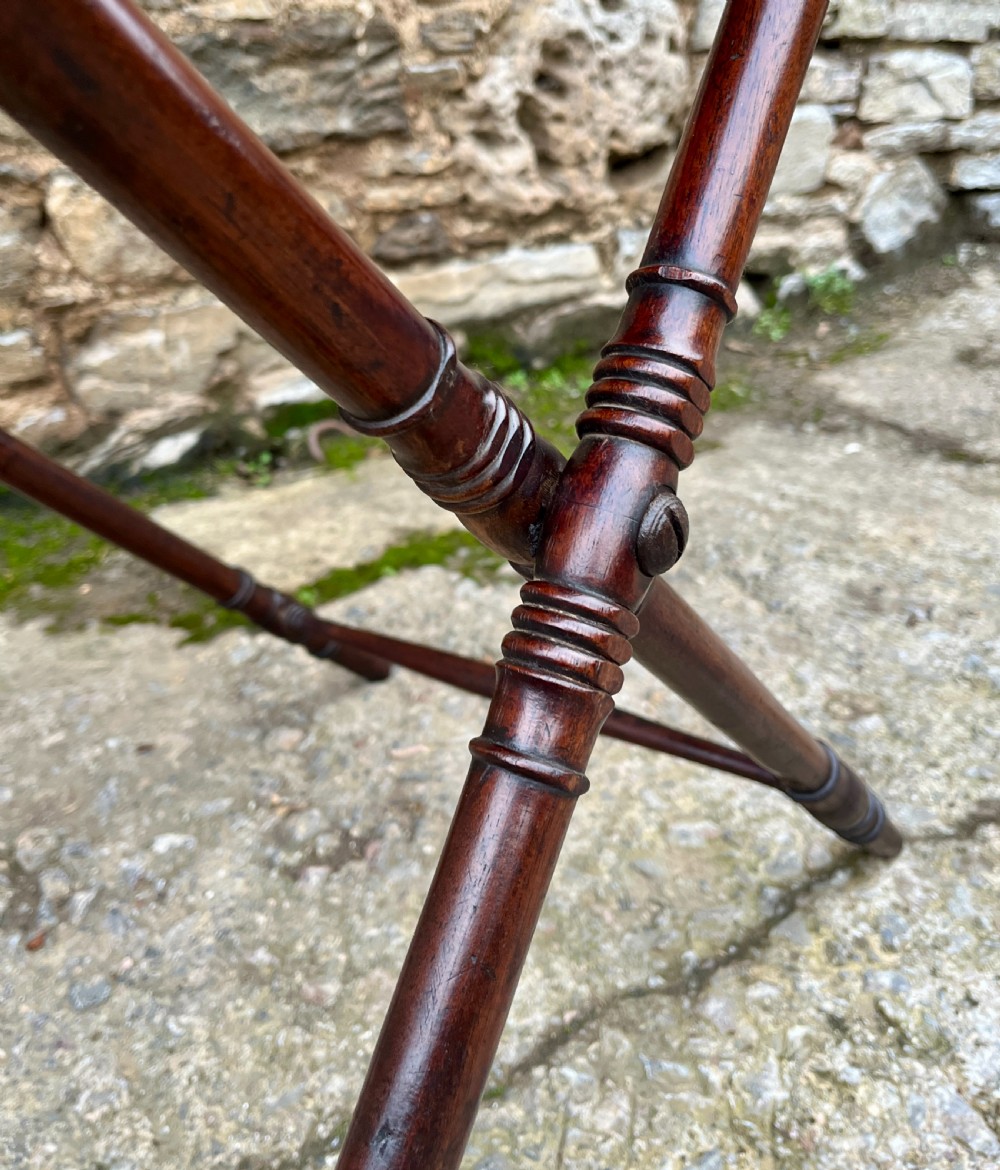 A Georgian mahogany folding butlers tray table with a scalloped gallery border, heart-shaped cut-out handles, and a turned X-frame stand. View IV