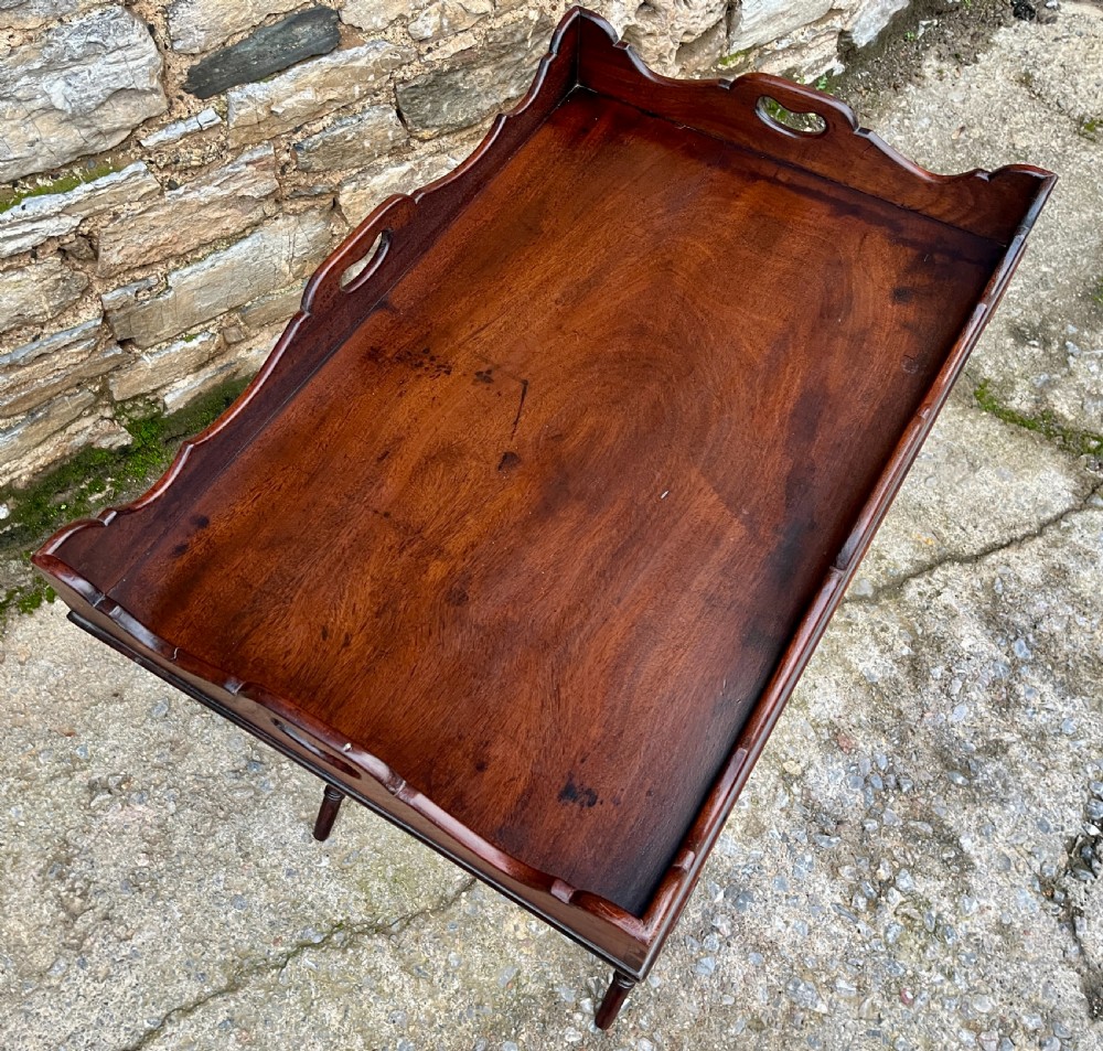 A Georgian mahogany folding butlers tray table with a scalloped gallery border, heart-shaped cut-out handles, and a turned X-frame stand. View V