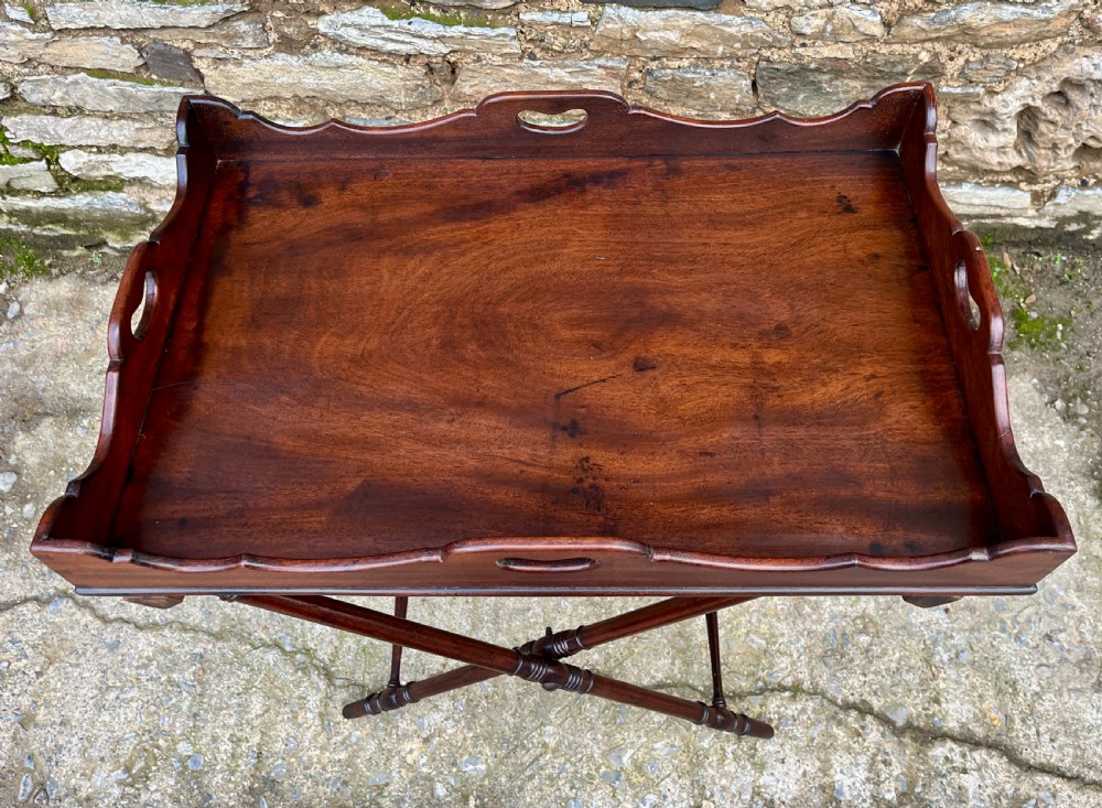 A Georgian mahogany folding butlers tray table with a scalloped gallery border, heart-shaped cut-out handles, and a turned X-frame stand. View VI