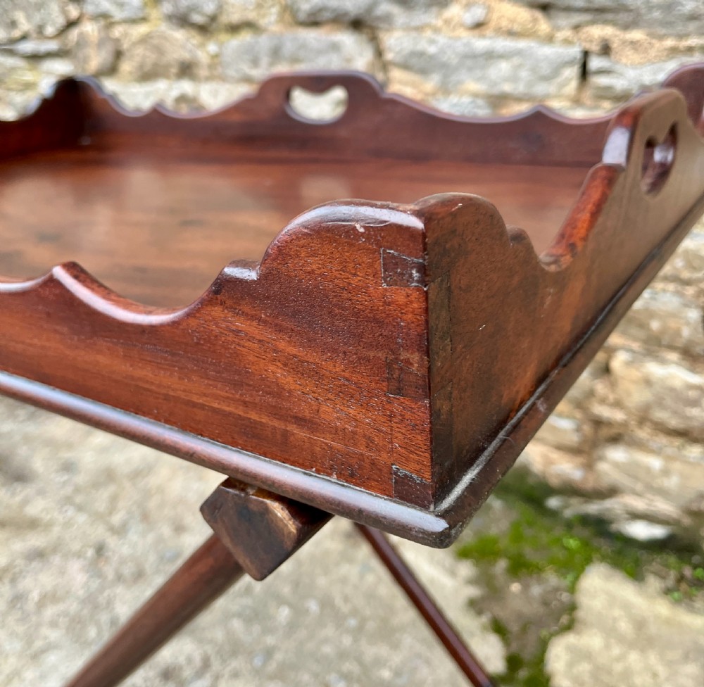 A Georgian mahogany folding butlers tray table with a scalloped gallery border, heart-shaped cut-out handles, and a turned X-frame stand. View VIII