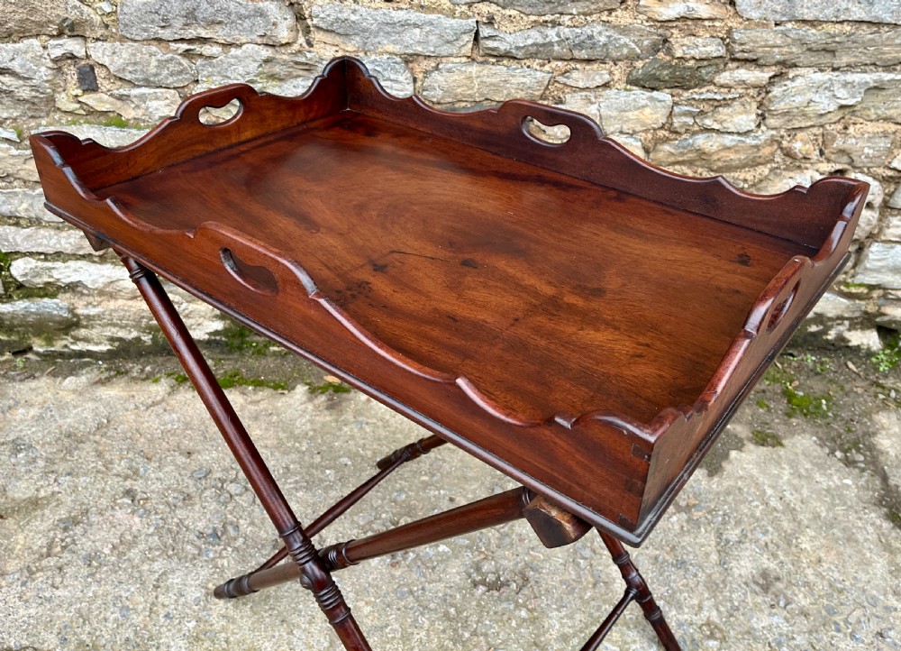 A Georgian mahogany folding butlers tray table with a scalloped gallery border, heart-shaped cut-out handles, and a turned X-frame stand. View XI