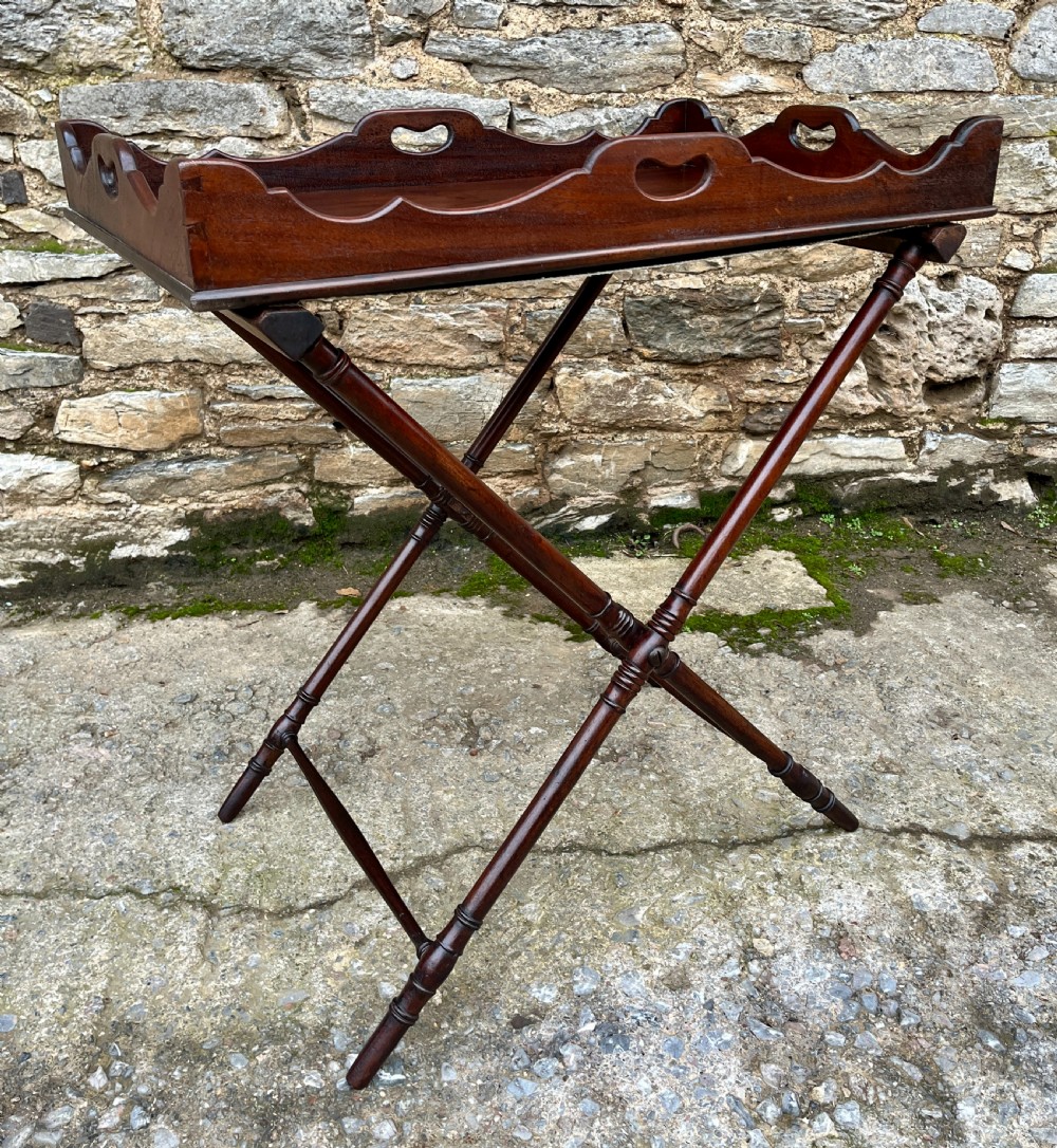 A Georgian mahogany folding butlers tray table with a scalloped gallery border, heart-shaped cut-out handles, and a turned X-frame stand. View XII