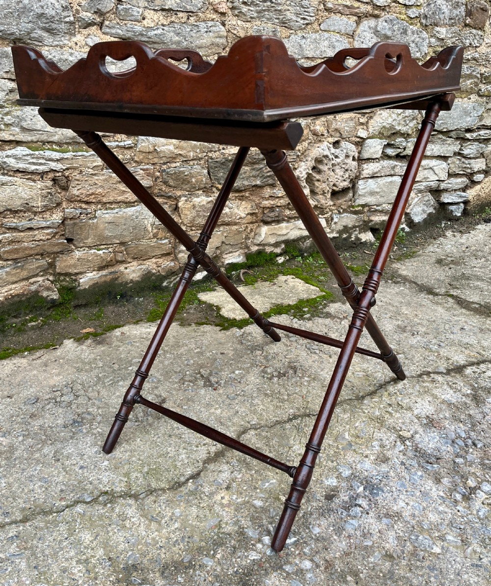 A Georgian mahogany folding butlers tray table with a scalloped gallery border, heart-shaped cut-out handles, and a turned X-frame stand. View XIV