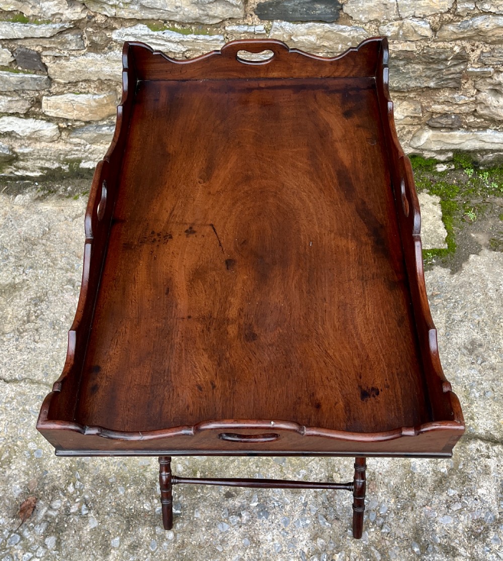 A Georgian mahogany folding butlers tray table with a scalloped gallery border, heart-shaped cut-out handles, and a turned X-frame stand. View XVII