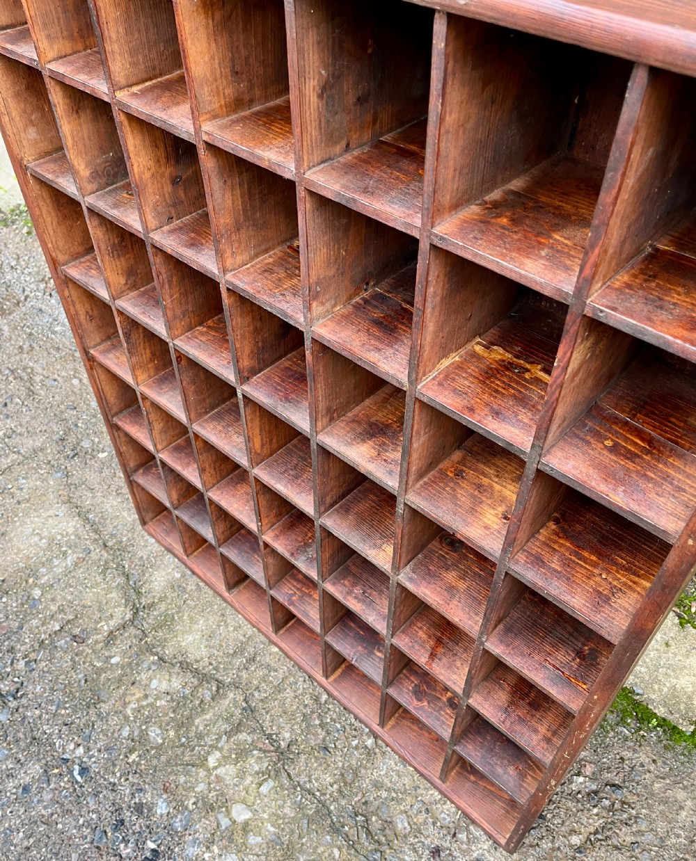 A large square wooden storage unit featuring a six-by-six grid of thirty-six rectangular cubbies made of dark stained pine. View VII