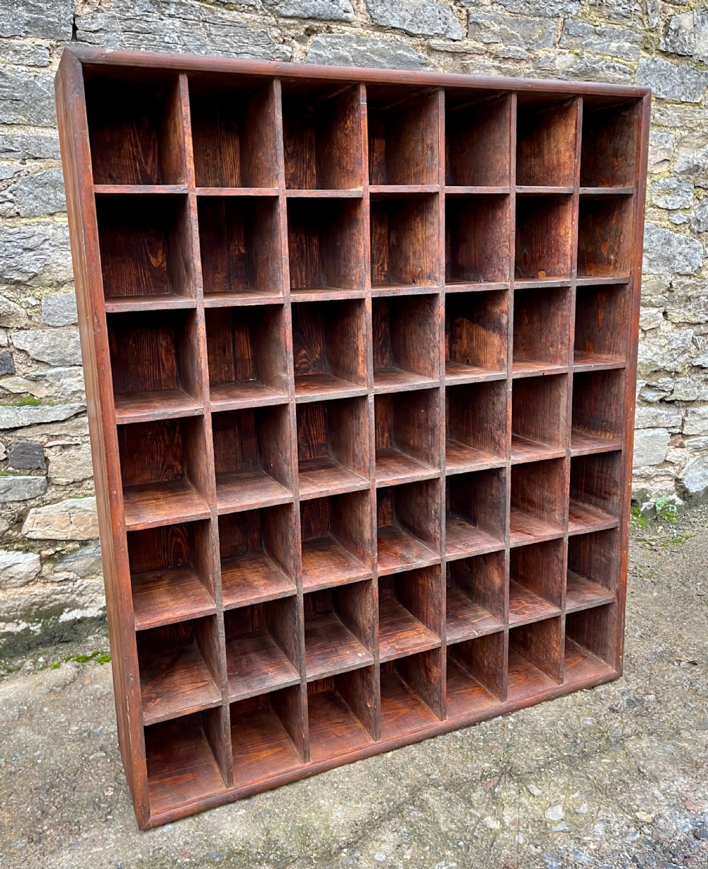A large square wooden storage unit featuring a six-by-six grid of thirty-six rectangular cubbies made of dark stained pine. View X