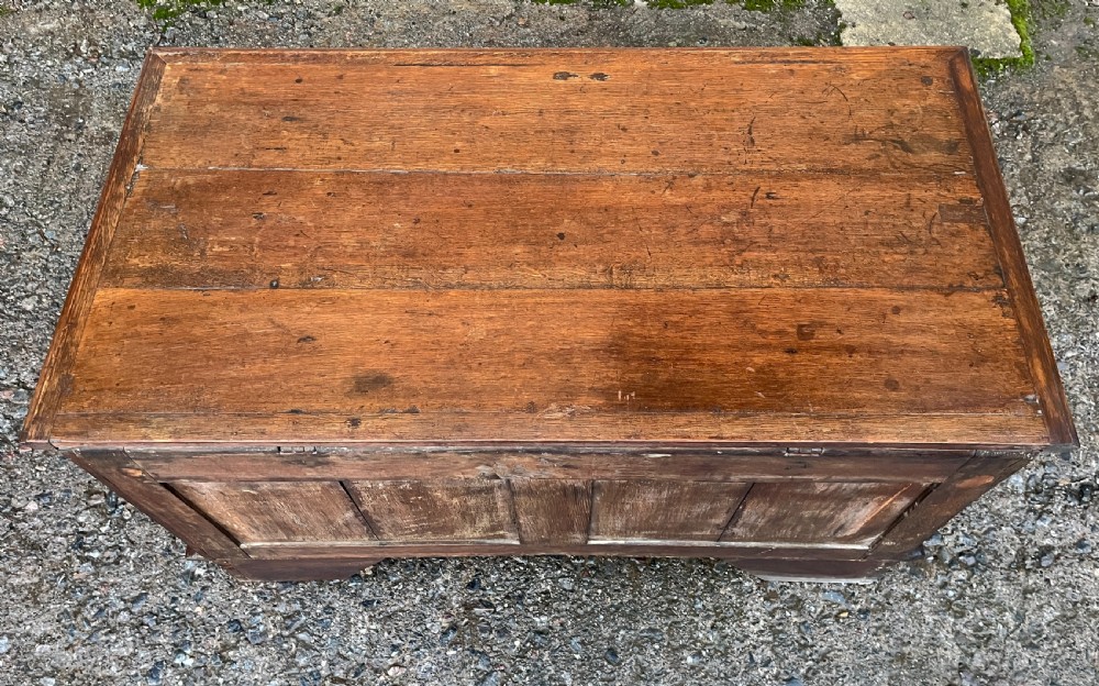 A solid oak blanket chest featuring dual fielded front panels, a central brass keyhole escutcheon, and a carved decorative apron along the base. View IV