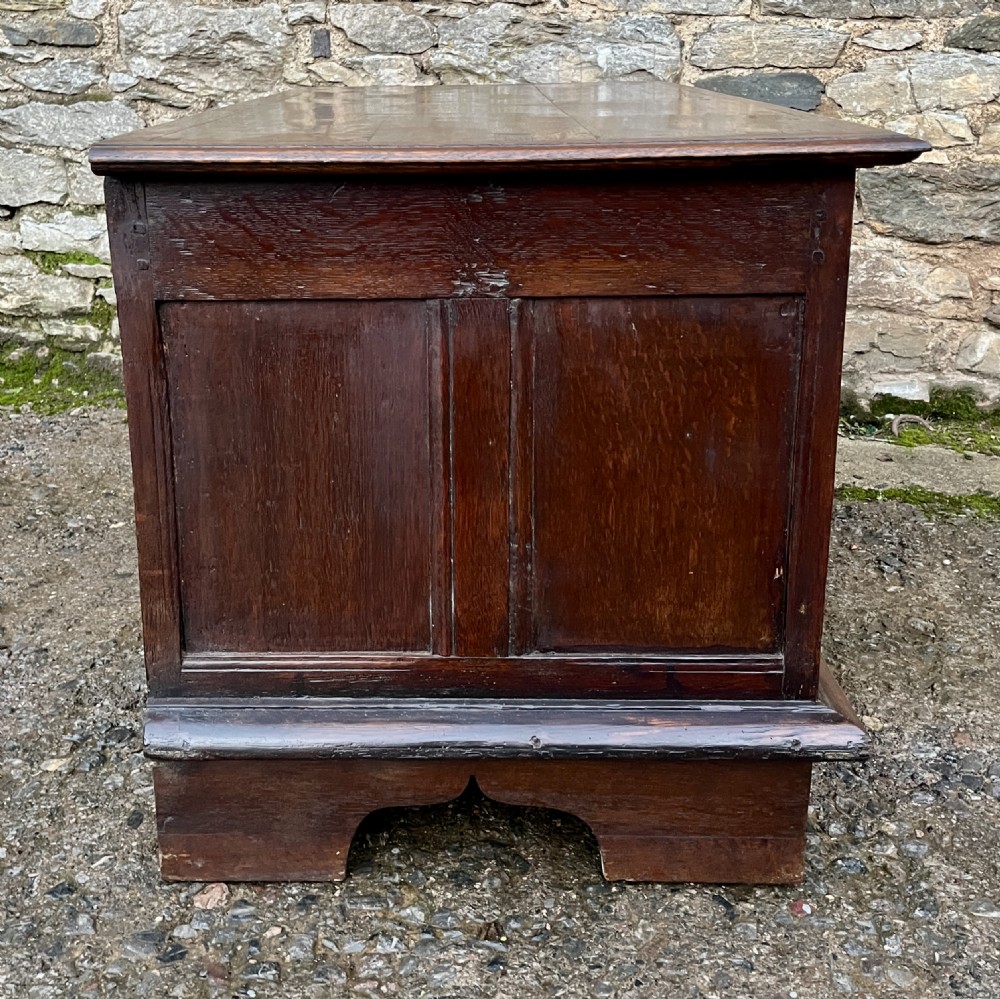A solid oak blanket chest featuring dual fielded front panels, a central brass keyhole escutcheon, and a carved decorative apron along the base. View XIII