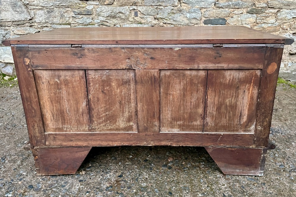 A solid oak blanket chest featuring dual fielded front panels, a central brass keyhole escutcheon, and a carved decorative apron along the base. View XVII