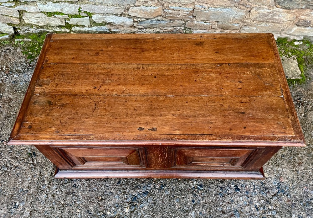 A solid oak blanket chest featuring dual fielded front panels, a central brass keyhole escutcheon, and a carved decorative apron along the base. View XIX