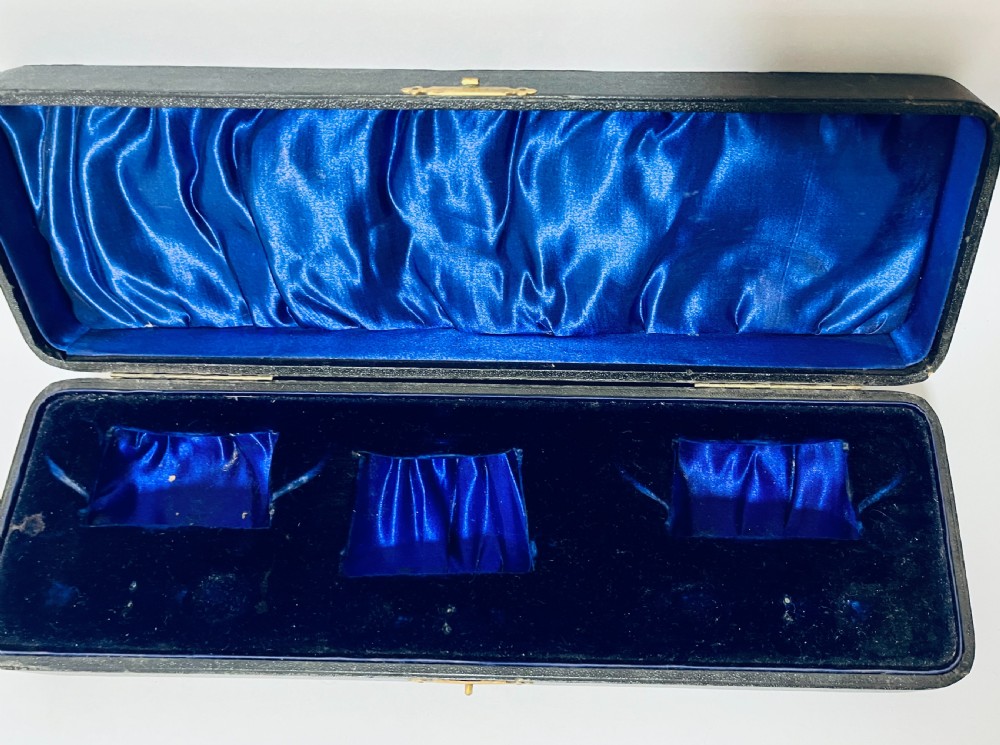 A three-piece Victorian silver condiment set with matching spoons displayed inside a fitted blue satin-lined dark presentation case. View XI
