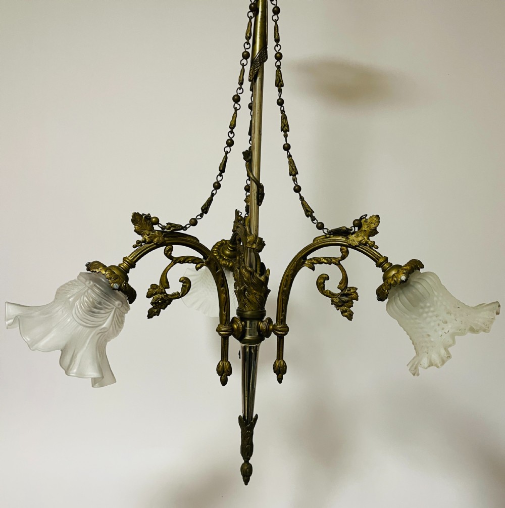A French Empire style bronze chandelier featuring three ornate scrolling arms with frosted glass ruffled shades and hanging chain details. View III