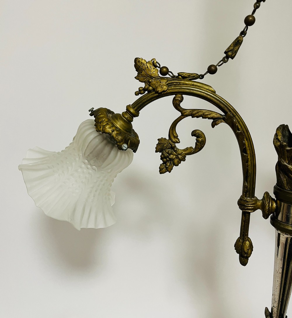 A French Empire style bronze chandelier featuring three ornate scrolling arms with frosted glass ruffled shades and hanging chain details. View IV