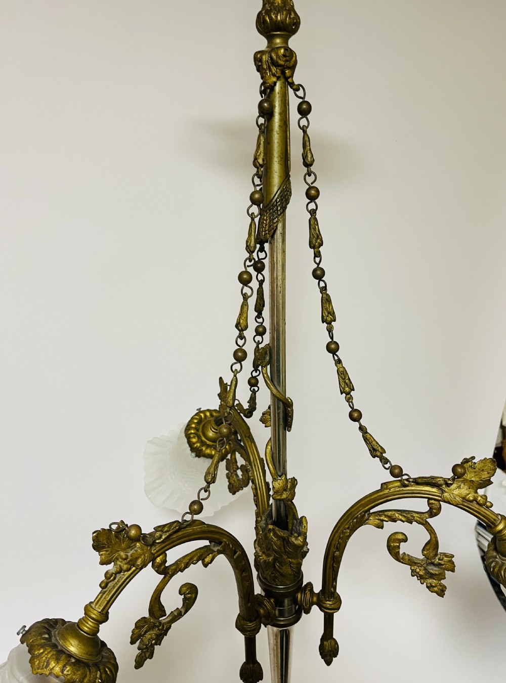A French Empire style bronze chandelier featuring three ornate scrolling arms with frosted glass ruffled shades and hanging chain details. View VI