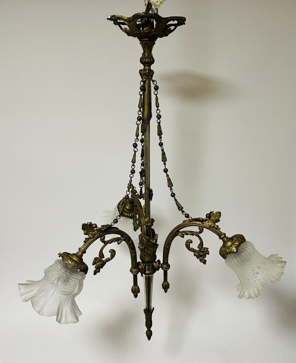 A French Empire style bronze chandelier featuring three ornate scrolling arms with frosted glass ruffled shades and hanging chain details. View IX
