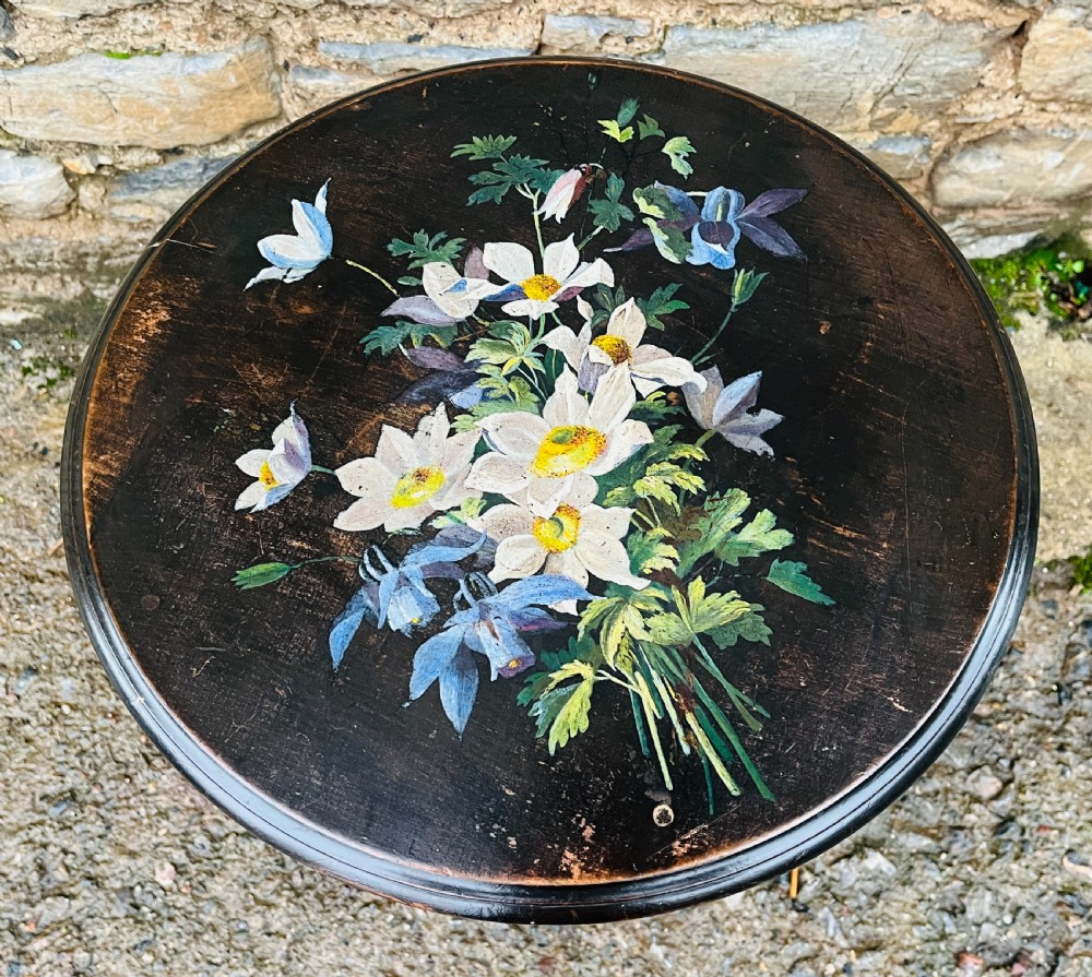 A circular two-tiered ebonised wooden side table featuring turned bobbin legs and hand-painted floral arrangements on both levels. View III