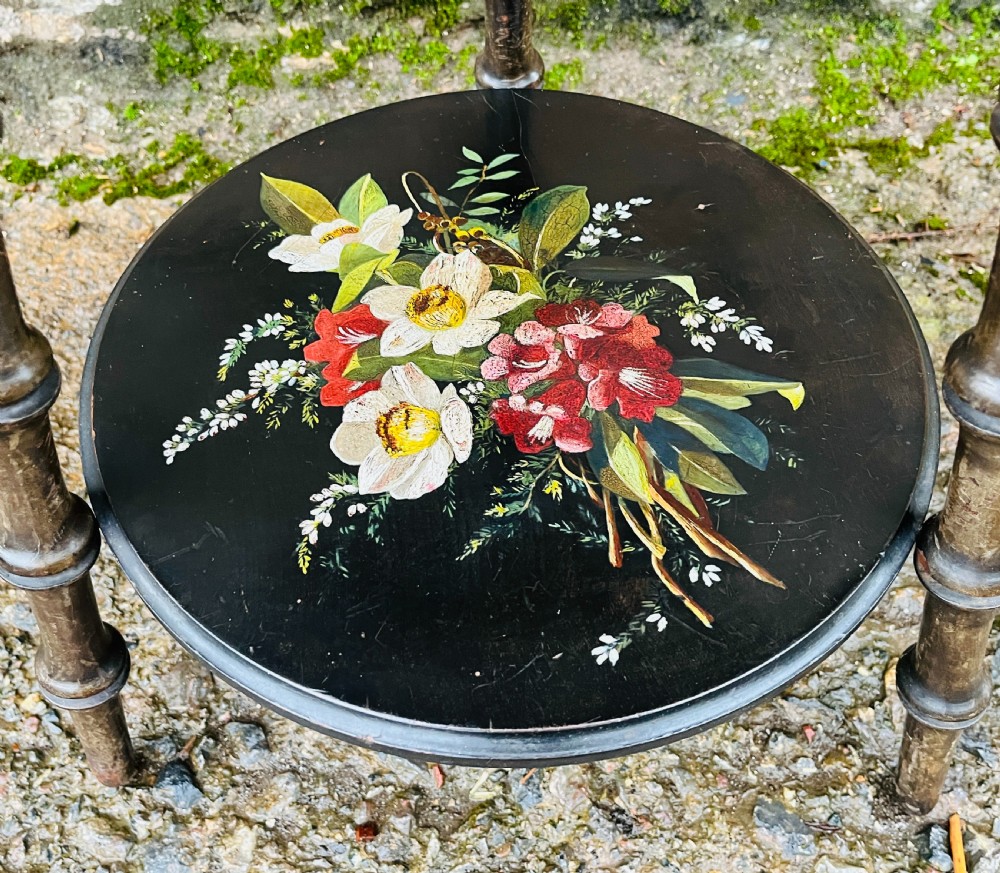 A circular two-tiered ebonised wooden side table featuring turned bobbin legs and hand-painted floral arrangements on both levels. View IV