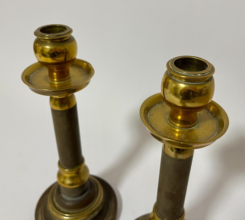 A pair of Edwardian turned brass candlesticks featuring circular stepped bases and alternating polished and patinated dark brass sections. View III