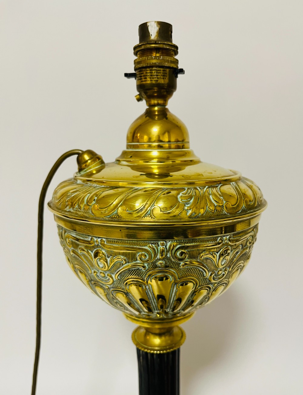 An antique Victorian embossed brass oil lamp converted into an electric table lamp with a reeded column and black circular base. View III
