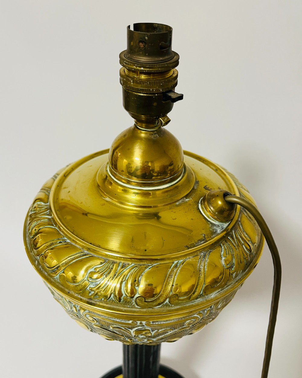 An antique Victorian embossed brass oil lamp converted into an electric table lamp with a reeded column and black circular base. View V