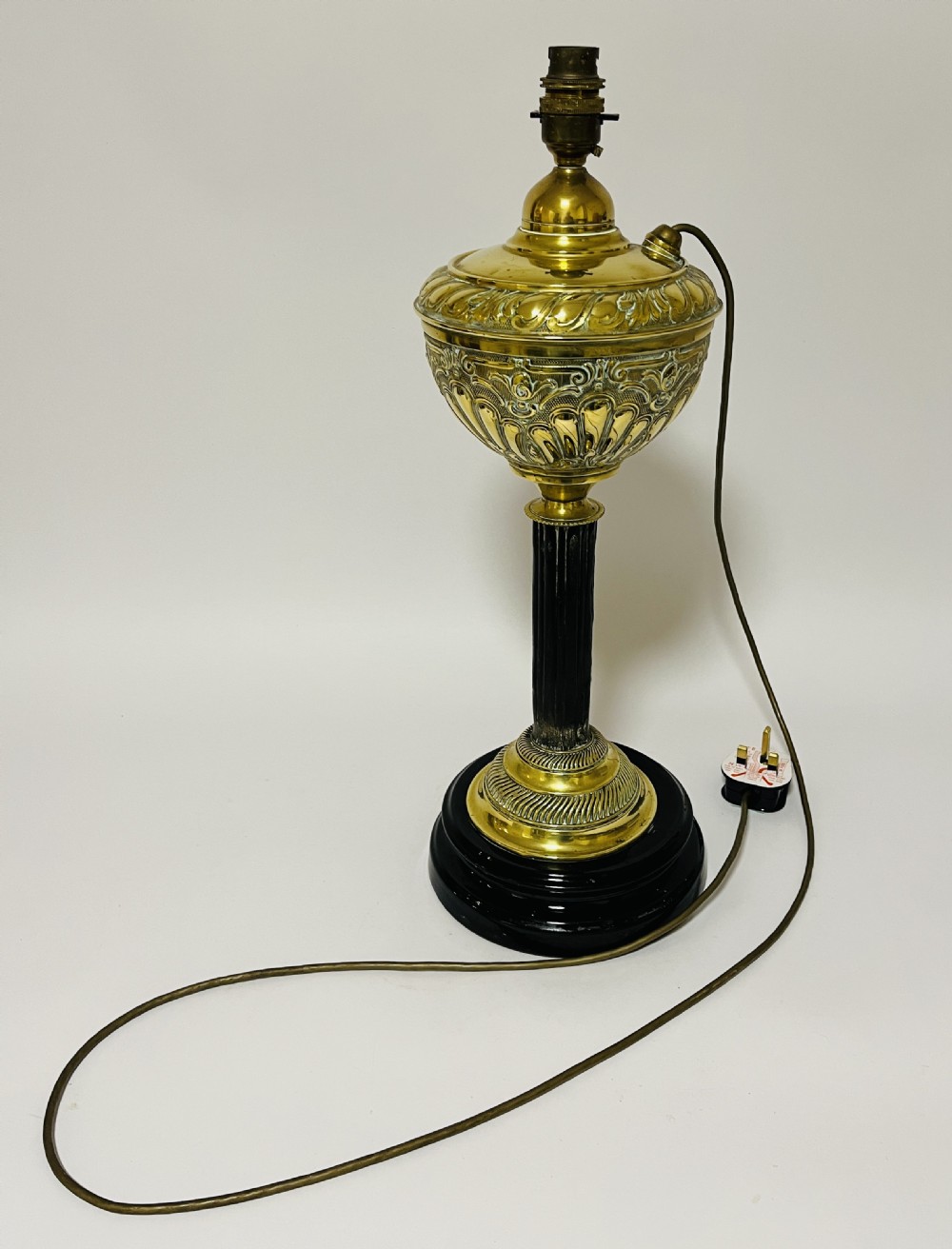 An antique Victorian embossed brass oil lamp converted into an electric table lamp with a reeded column and black circular base. View IX