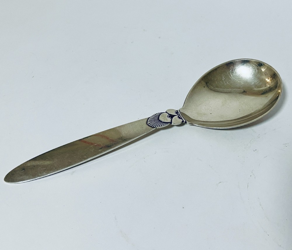 A sterling silver serving spoon in the Georg Jensen Cactus pattern featuring a smooth oval bowl and a tapered handle with stylised leaf embellishments. View II