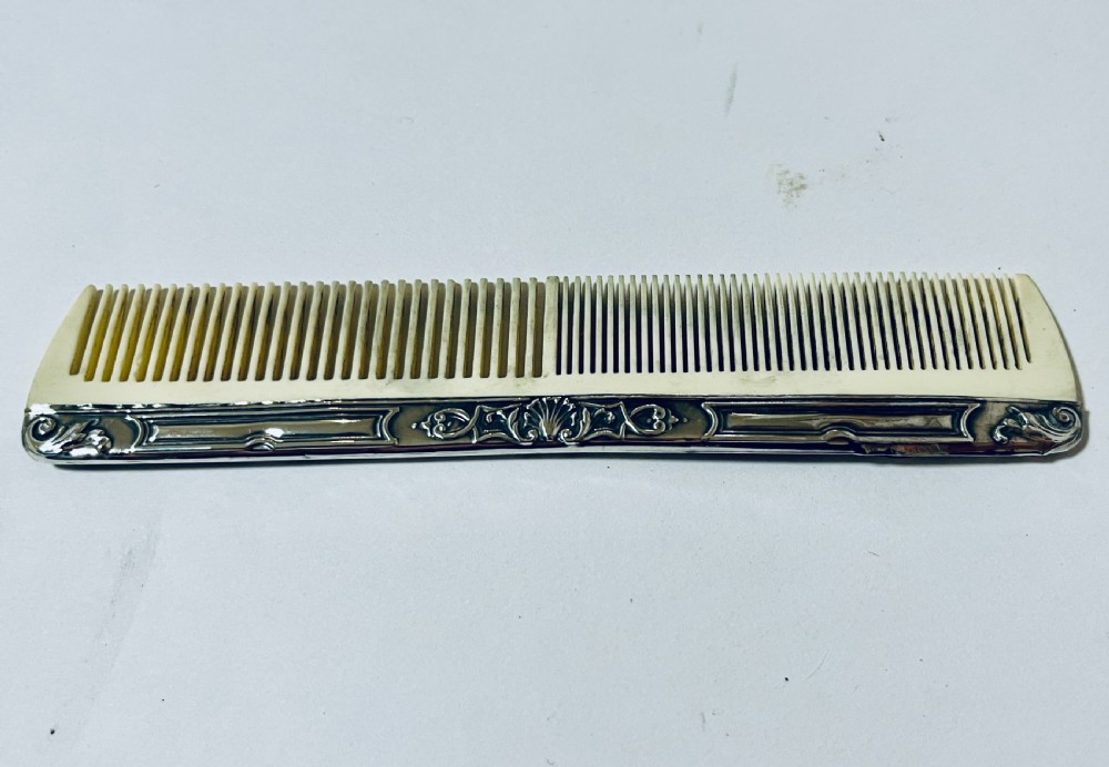 An open green textured box containing a French silver vanity set with a silver hairbrush, comb, and round lidded jar set into a yellow silk lining. View XI