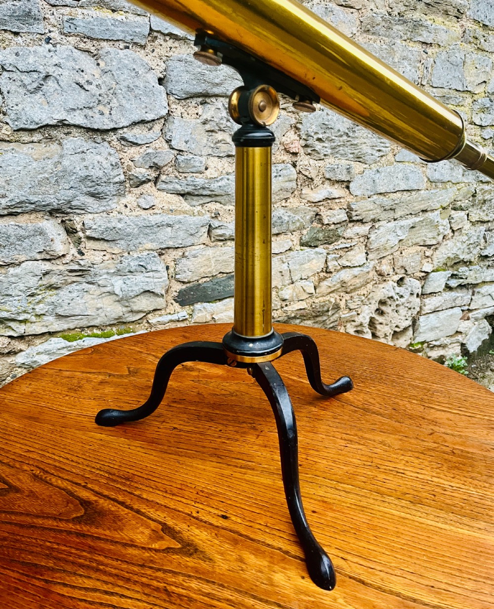 A Victorian brass library telescope supported by a black cast iron tripod desktop base. View IV