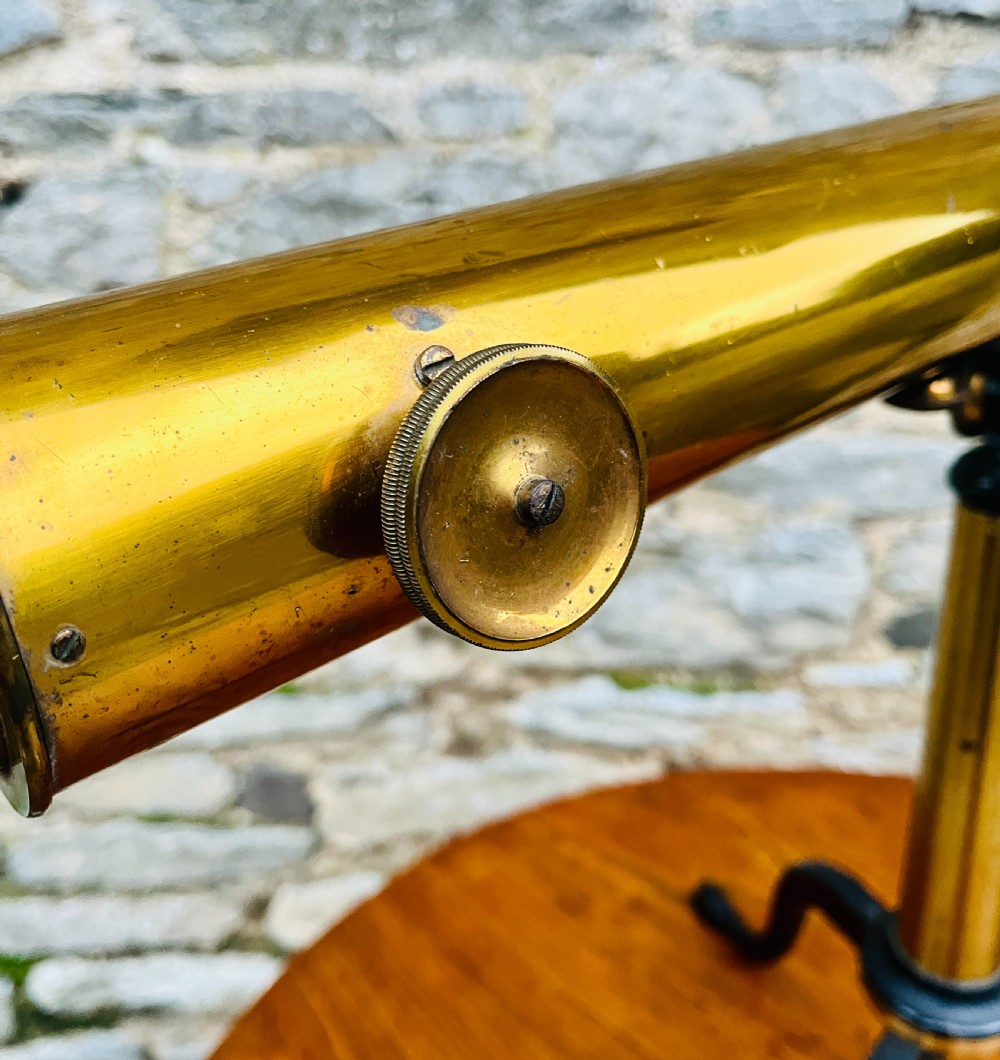 A Victorian brass library telescope supported by a black cast iron tripod desktop base. View V