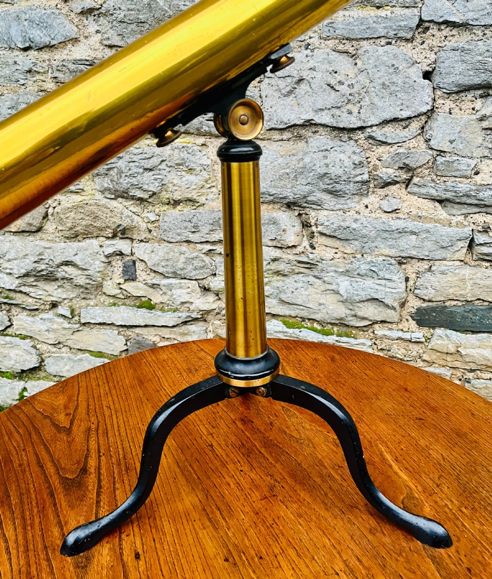 A Victorian brass library telescope supported by a black cast iron tripod desktop base. View IX