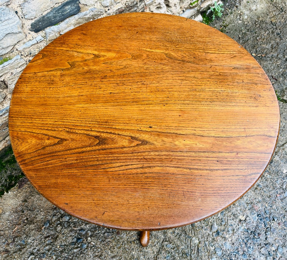 A circular Georgian oak tilt-top table resting on a central turned pedestal with three sweeping tripod legs. View VII