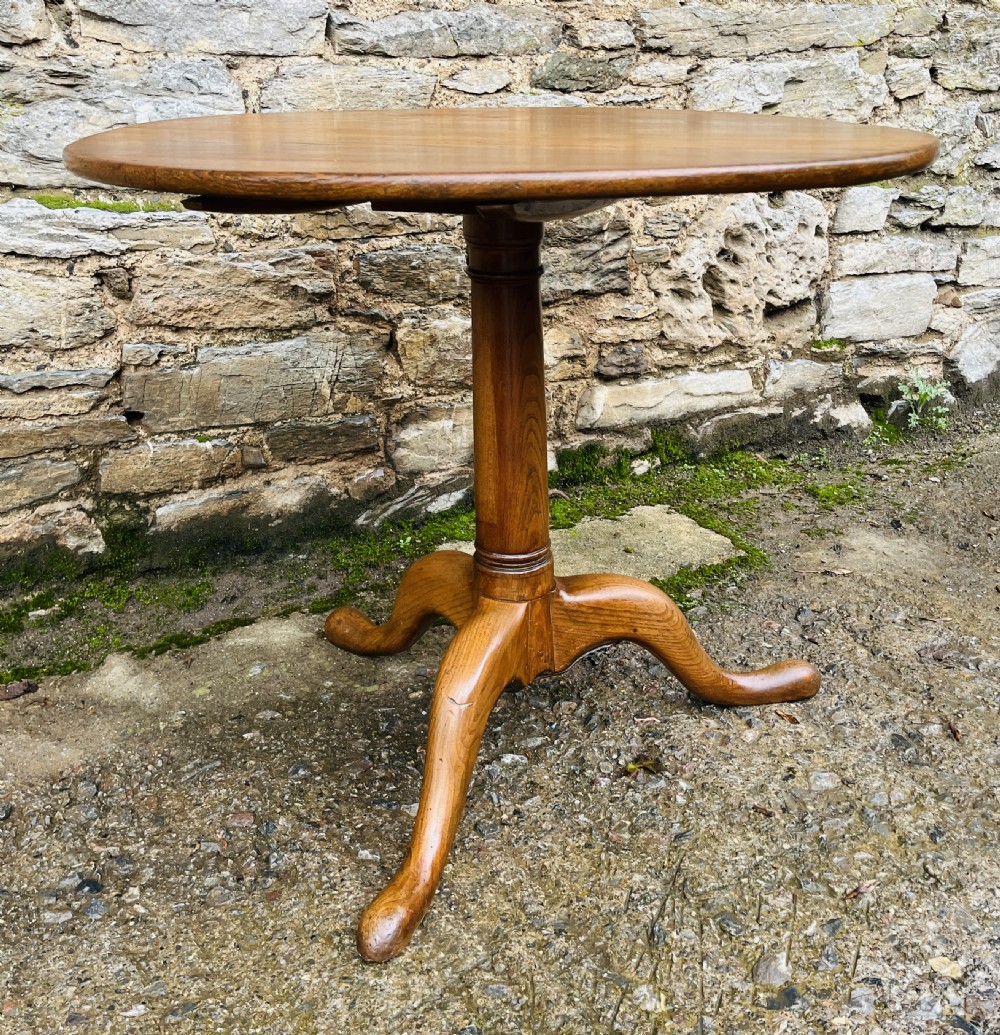 A circular Georgian oak tilt-top table resting on a central turned pedestal with three sweeping tripod legs. View XII