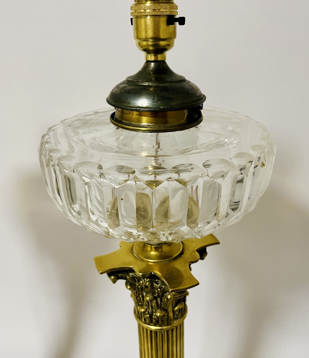 A pair of brass Corinthian column table lamps featuring stepped square plinths, fluted columns, acanthus capitals, and cut glass reservoirs. View IV