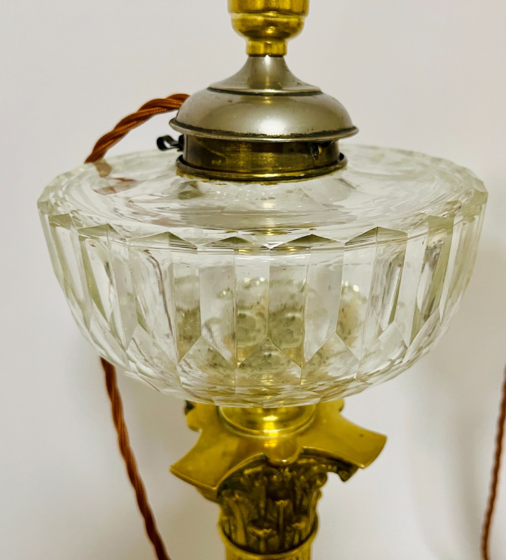 A pair of brass Corinthian column table lamps featuring stepped square plinths, fluted columns, acanthus capitals, and cut glass reservoirs. View VIII