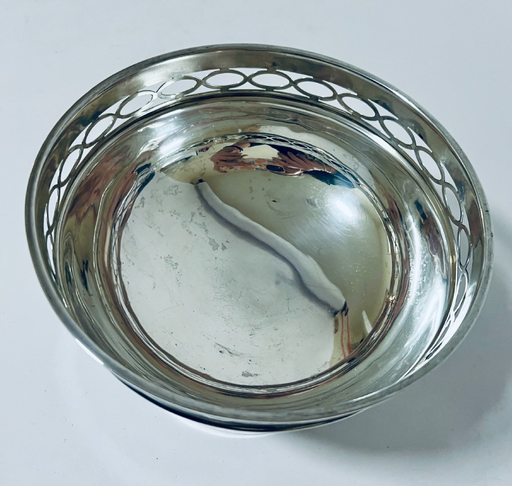 A polished silver pedestal rose bowl featuring a pierced rim with an interlocking oval gallery pattern. View V