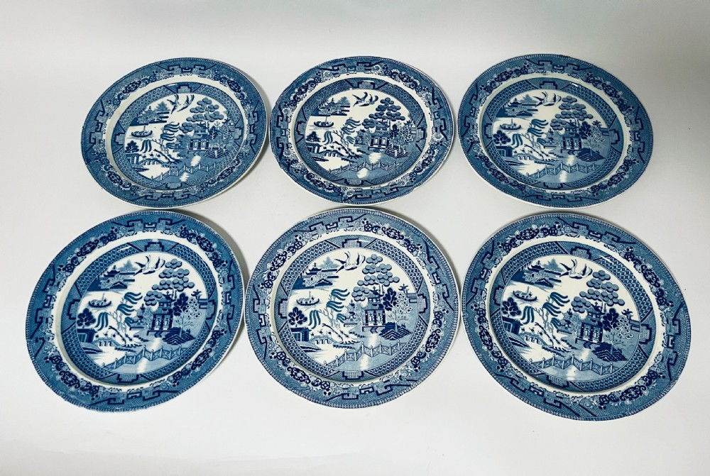 A set of six circular earthenware plates decorated with classic cobalt blue and white Willow Pattern transferware illustrations. View II